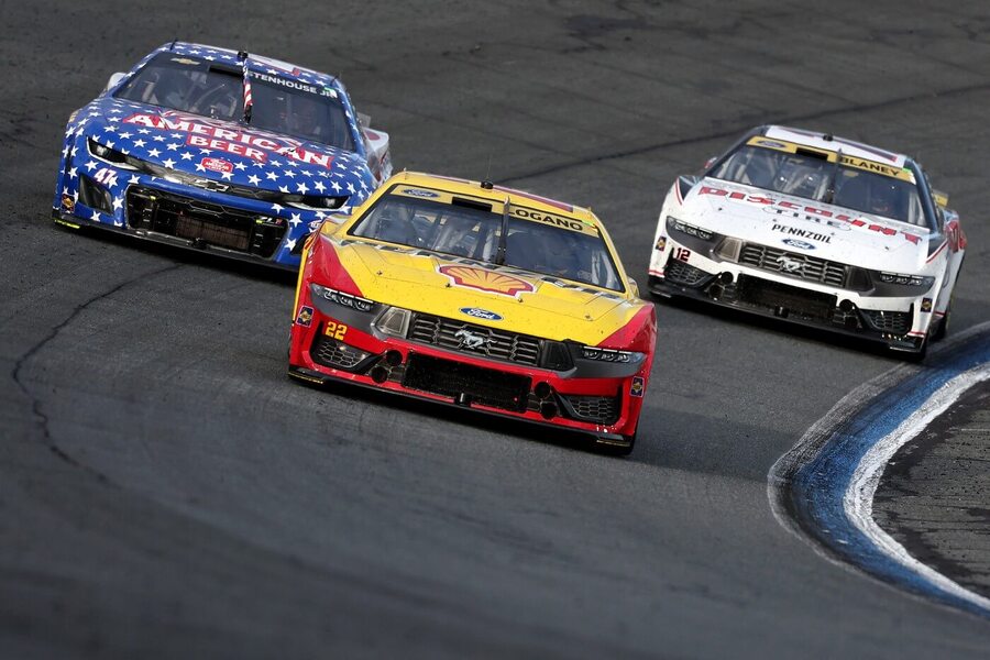 Joey Logano při závodu NASCAR, následován Rickym Stenhousem Jr. (vlevo) a Ryanem Blaineym